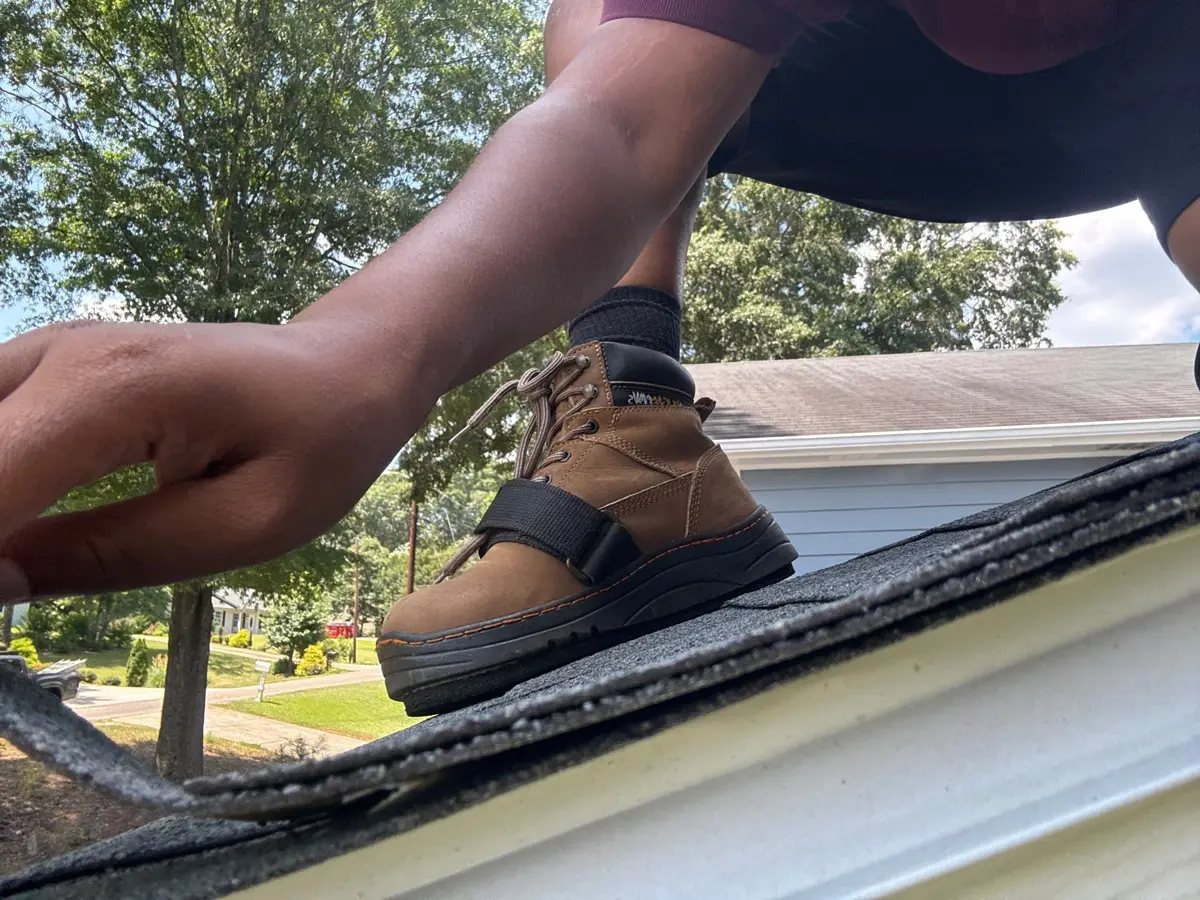 Worker installing roofing material along a roof edge and gutter, Southern Premier Roofing work near Monroe GA