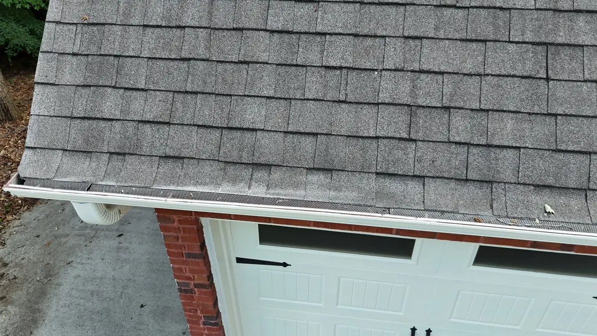 Shingled garage roof edge with gutters and brick facade, Southern Premier Roofing work near Arcade GA