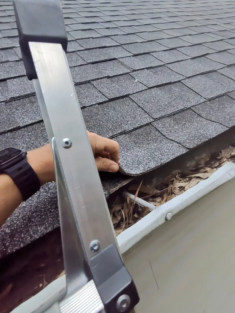 Roof shingles and gutter filled with leaves beside measuring tool, Southern Premier Roofing work near Dacula GA