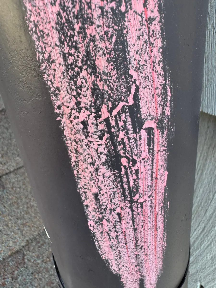 Close-up shows heavily weathered pink-streaked exterior downspout surface, Southern Premier Roofing work near Dacula GA