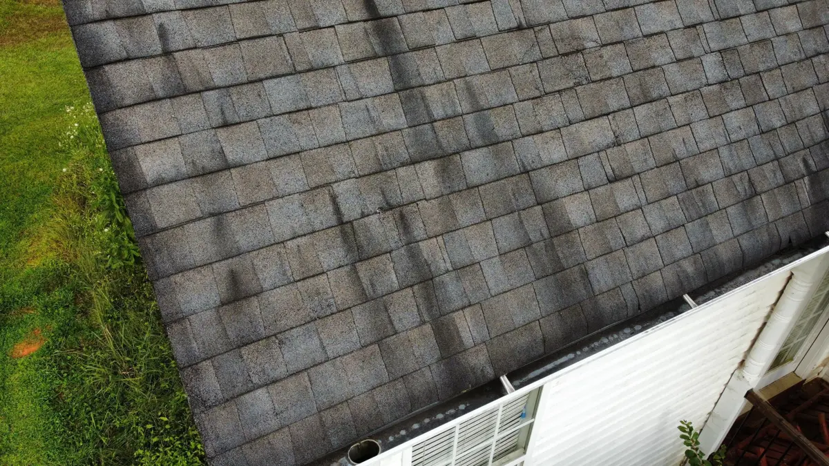 Roof slope with gray shingles and gutter edge beside exterior wall, Southern Premier Roofing work near Bishop GA