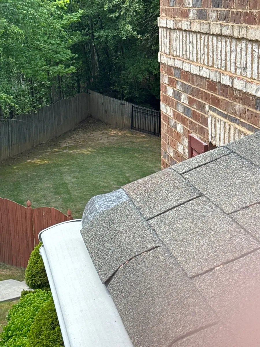 Close view of roof shingles beside white gutter and brick wall, Southern Premier Roofing work near Buford GA