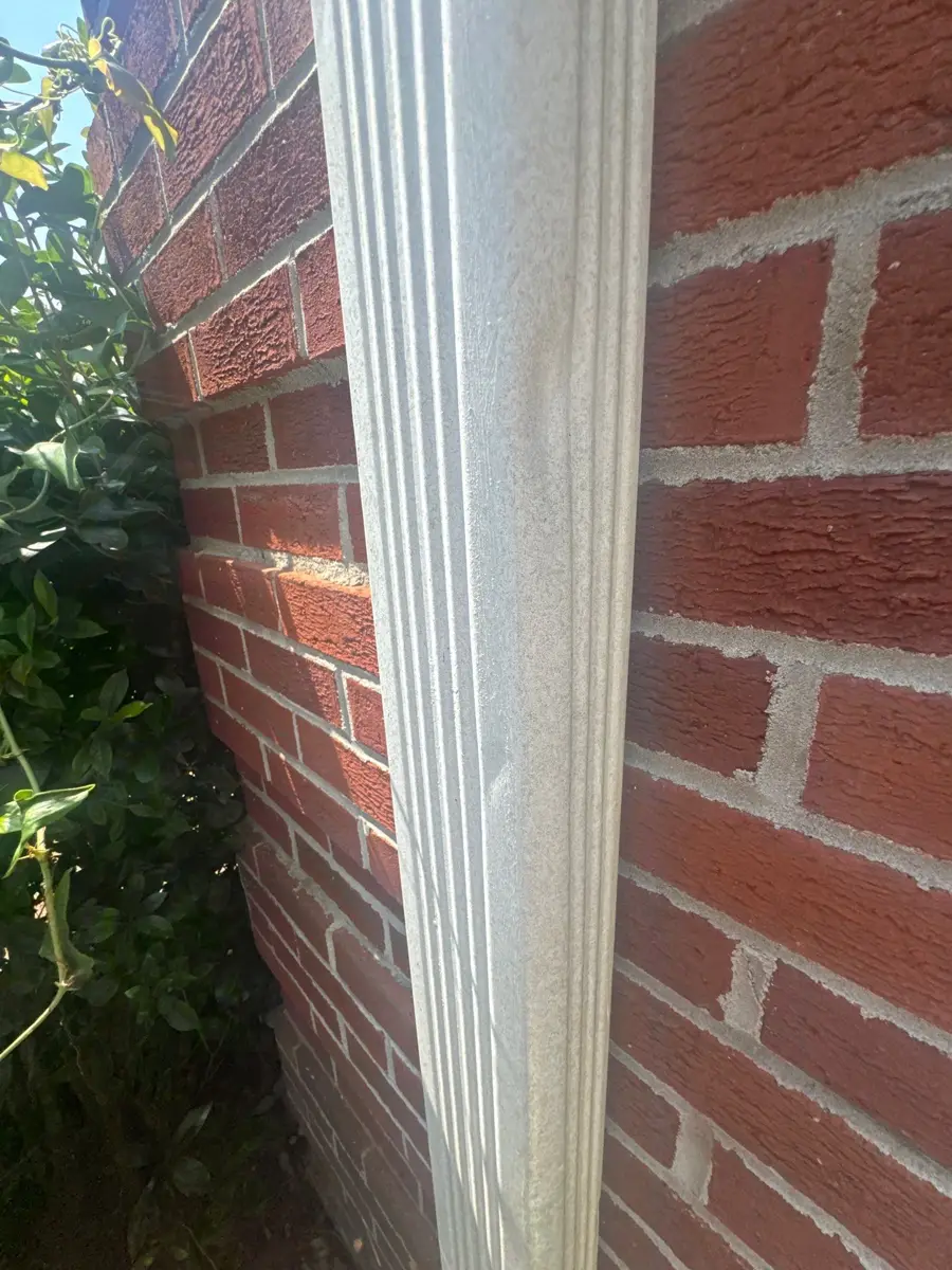 Close view of white gutter beside red brick wall, Southern Premier Roofing work near Carl GA