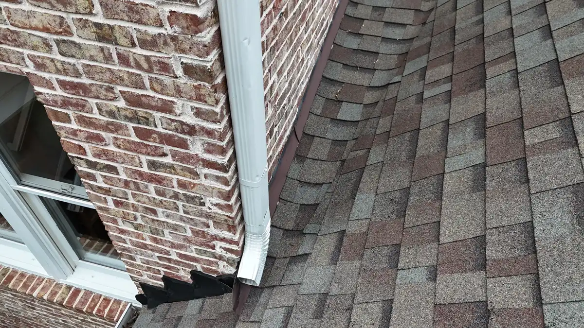 Shingles and flashing detail beside brick wall and gutter, Southern Premier Roofing work near Rest Haven GA