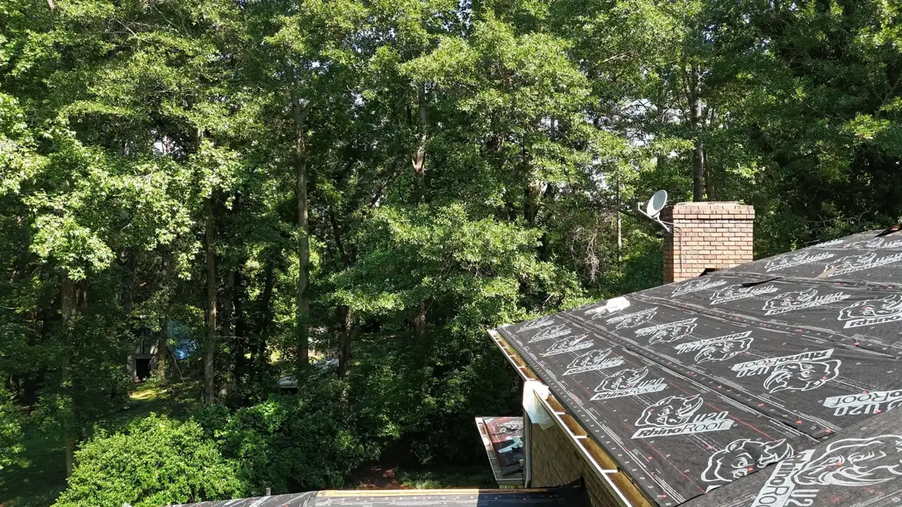 Roof replacement underlayment covers a sloped residential roof beside wooded surroundings in Athens GA