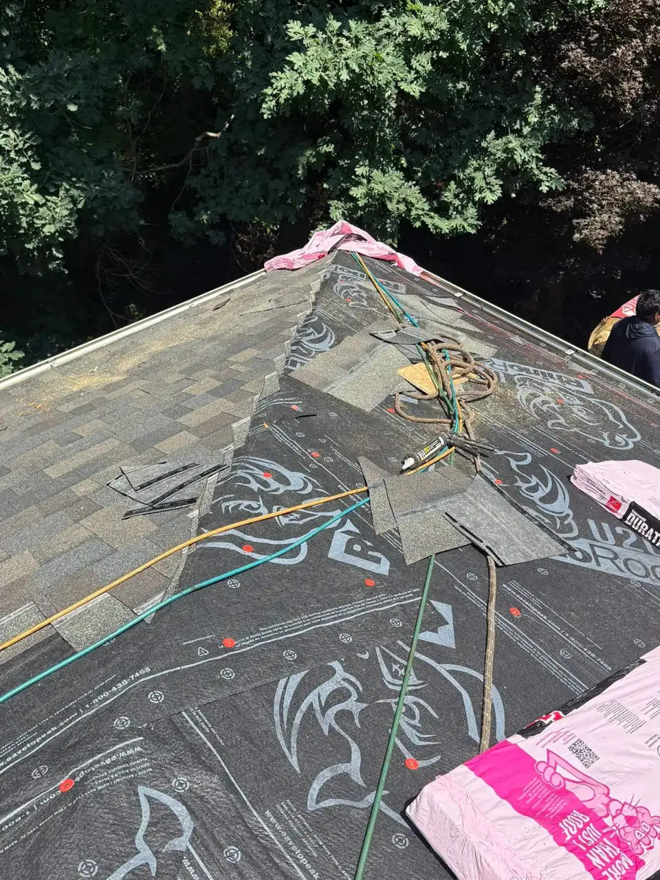 Roof underlayment, shingles, tools, and safety ropes visible during replacement in Athens GA