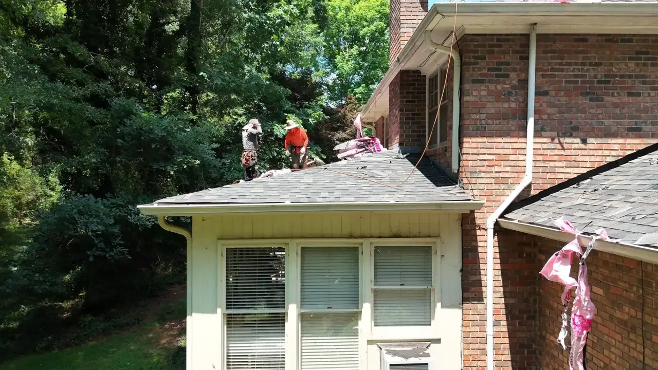 Workers stand on a shingled roof above siding and windows in Athens GA