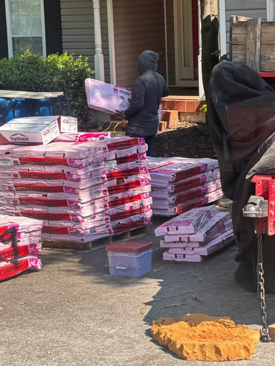 Roofing materials and bundled shingle packages sit outside a residential home in Bethlehem, Georgia.