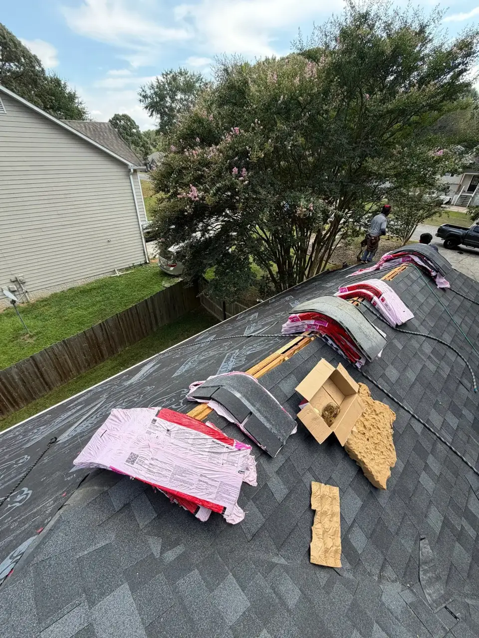 Roof in Bethlehem GA covered with shingles, roofing materials, and exposed underlayment beside a residential yard