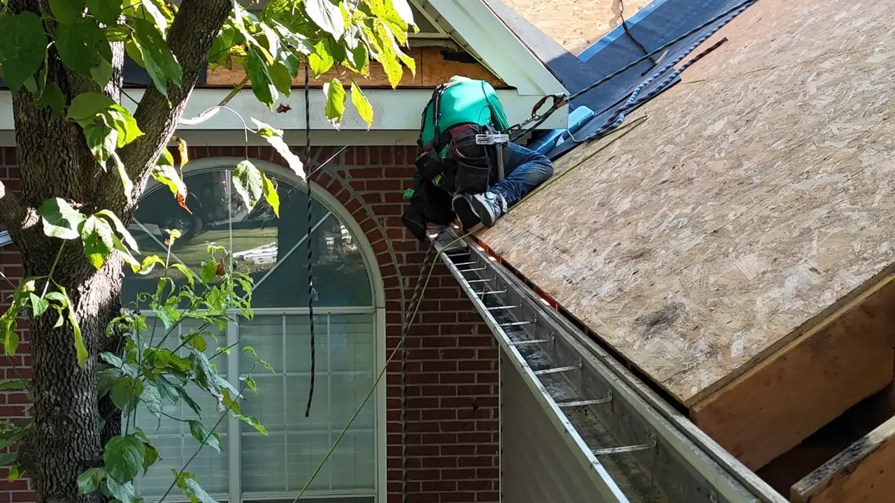 Roofer working on plywood roof sheathing above a brick home in Bethlehem GA