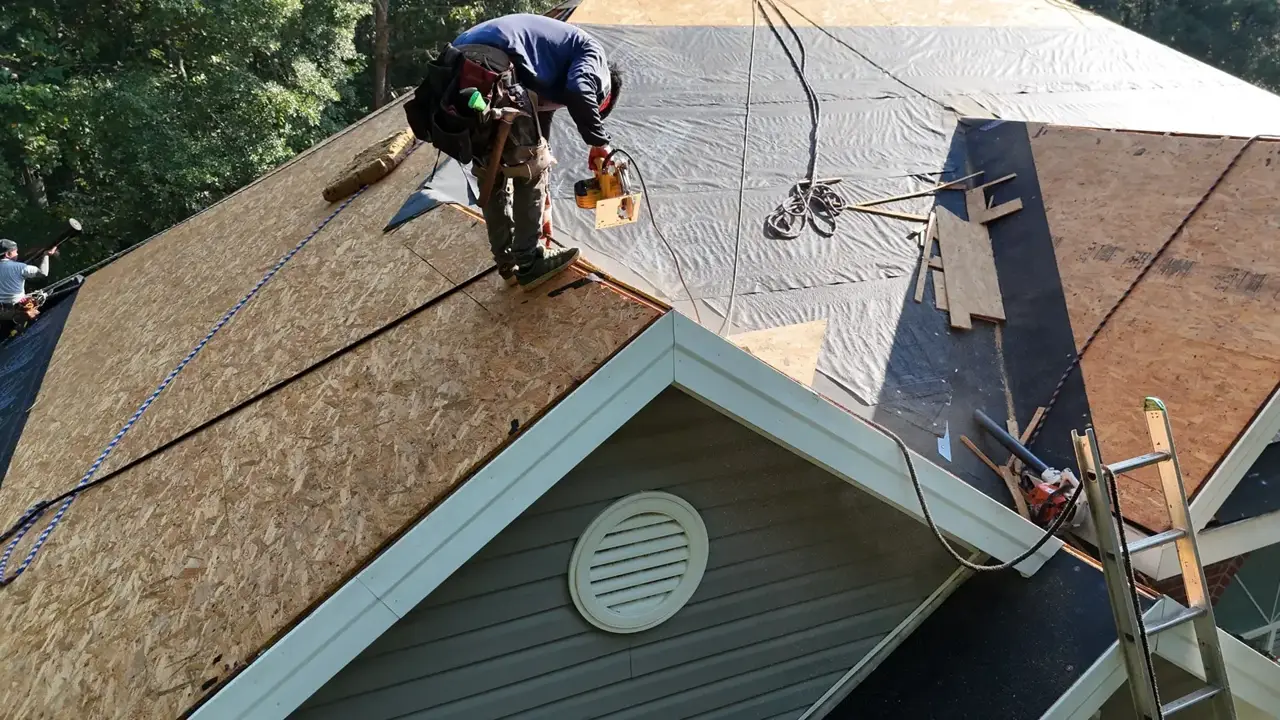 Worker installs roofing materials above a gable with siding and circular vent in Bethlehem, Georgia.