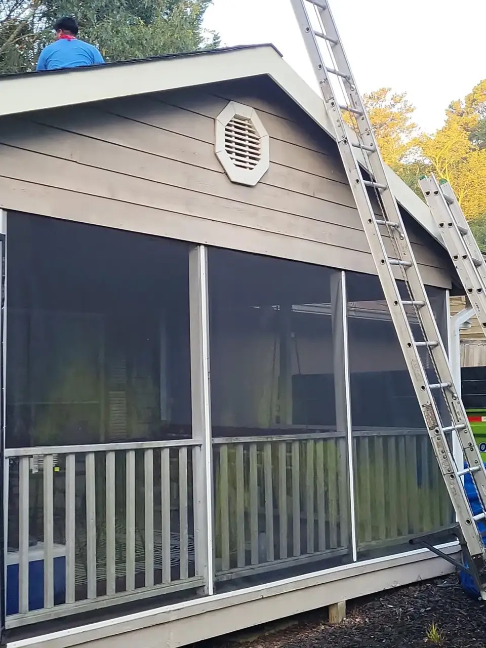 Screened porch with roof worker, vent, and extension ladder visible outside a Conyers GA residence.