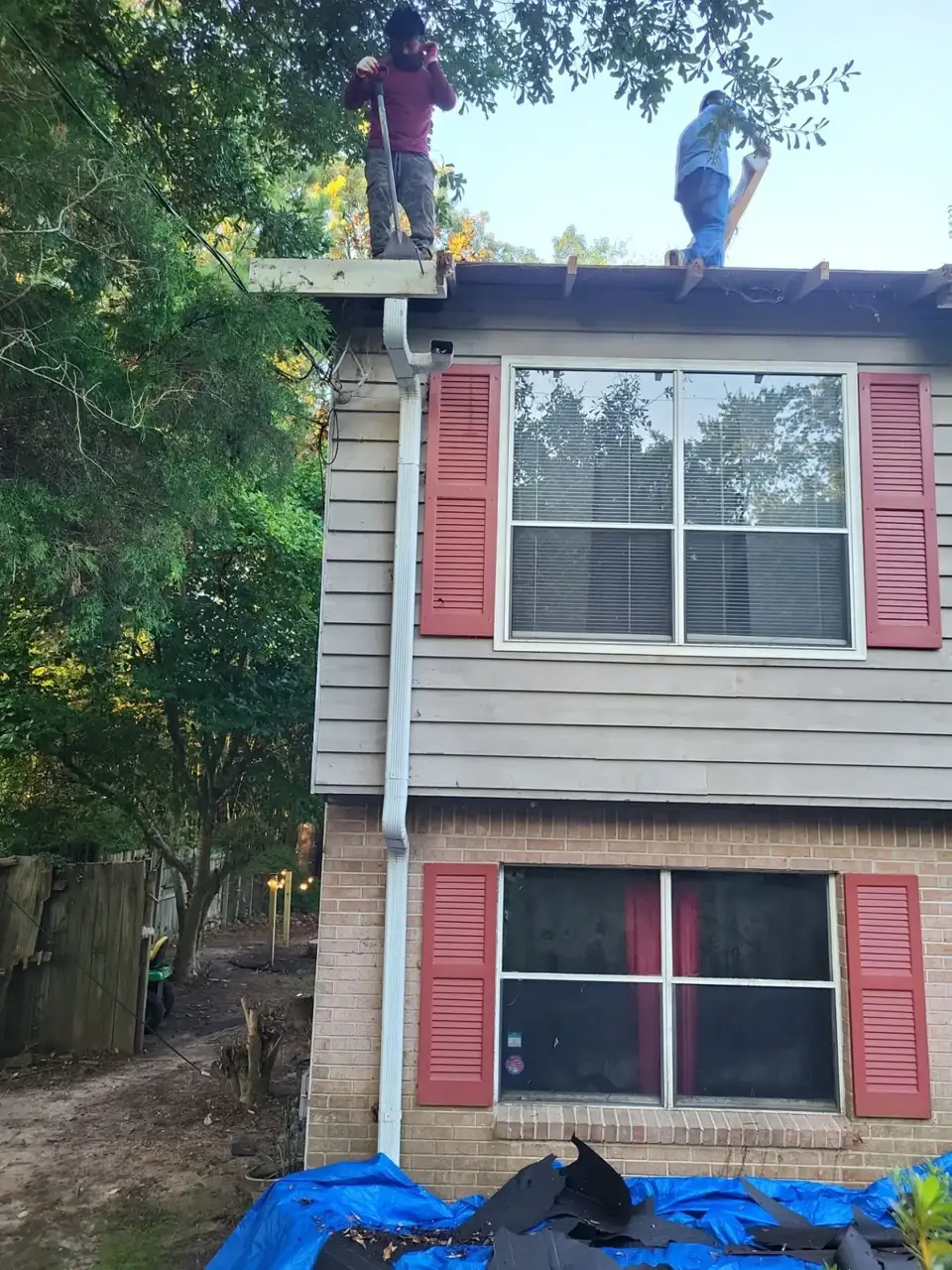 Workers stand on a roof beside siding, shutters, gutter, and blue tarp in Conyers GA.