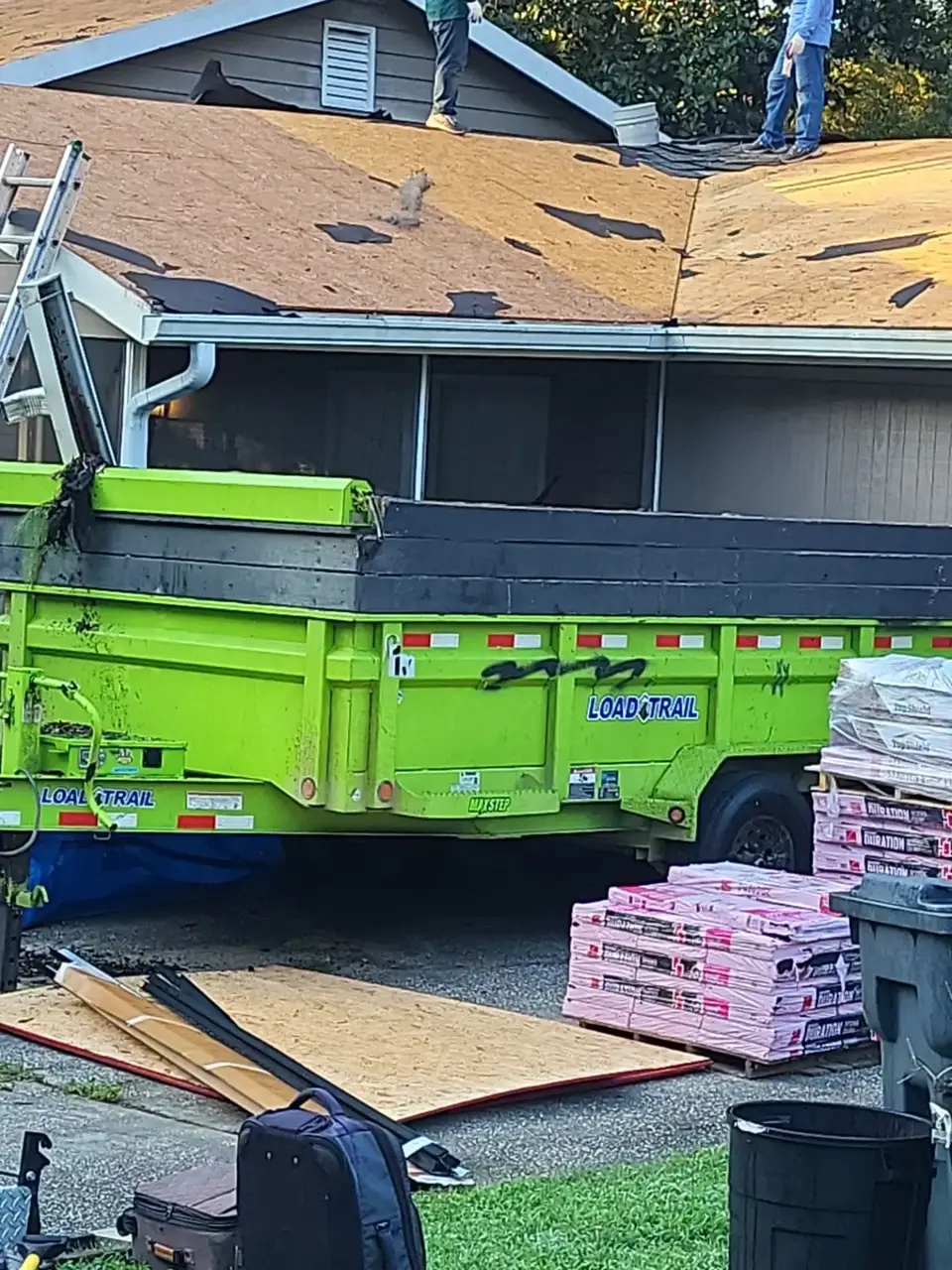 Roof decking, workers, green dumpster, shingle bundles, and roofing materials are visible in Conyers GA.