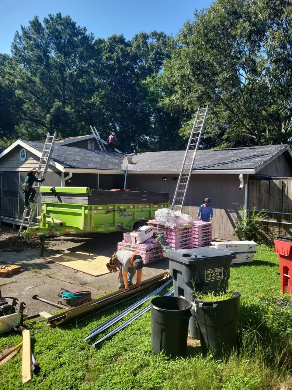 Workers, ladders, roof underlayment, dumpster, shingle bundles, and scattered materials appear at a Conyers GA home.