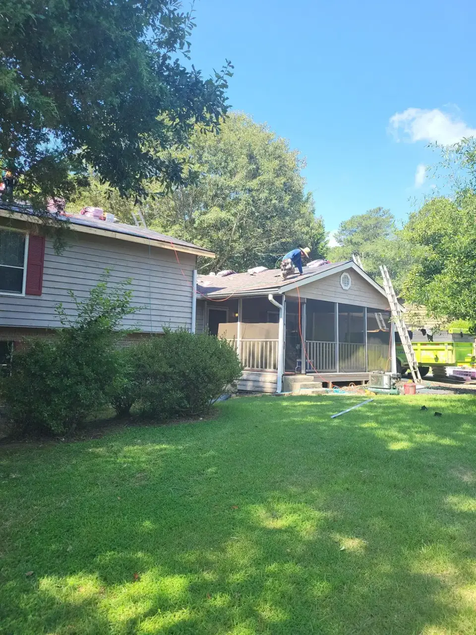 Workers on a shingle-covered residential roof beside screened porch in Conyers GA