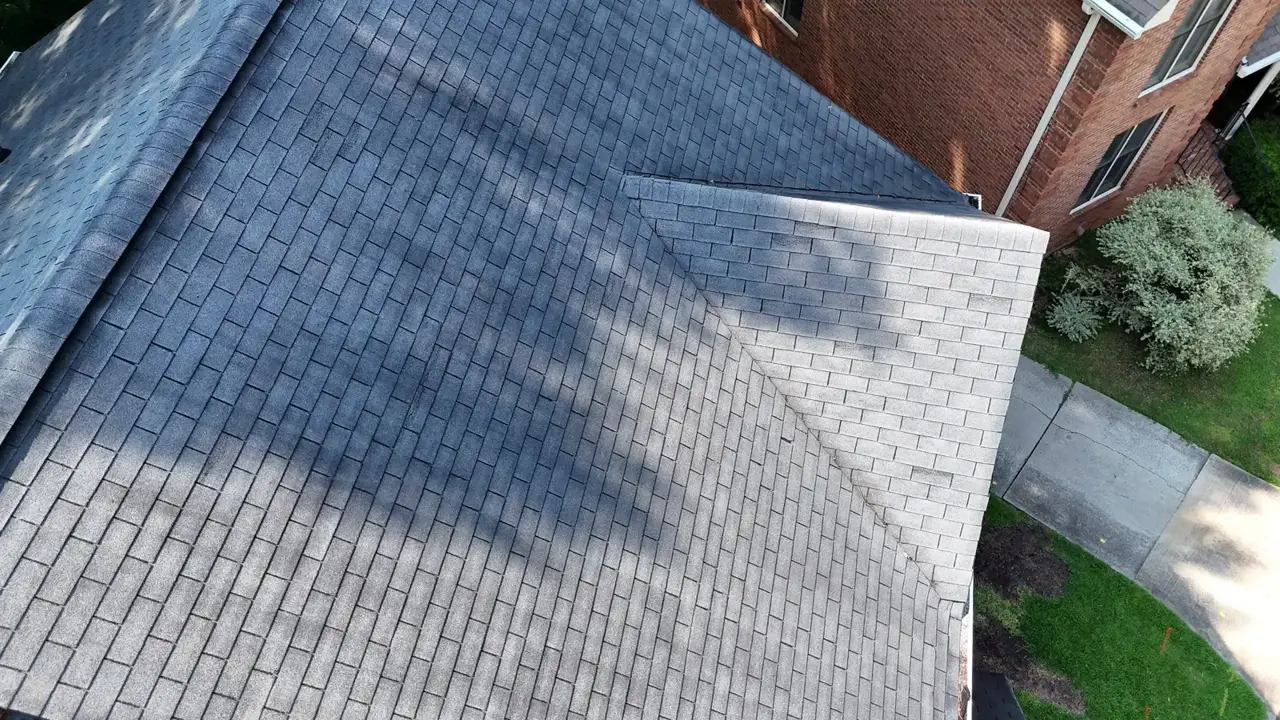Aerial view of gray shingle roof beside a brick home and concrete walkway in Decatur GA