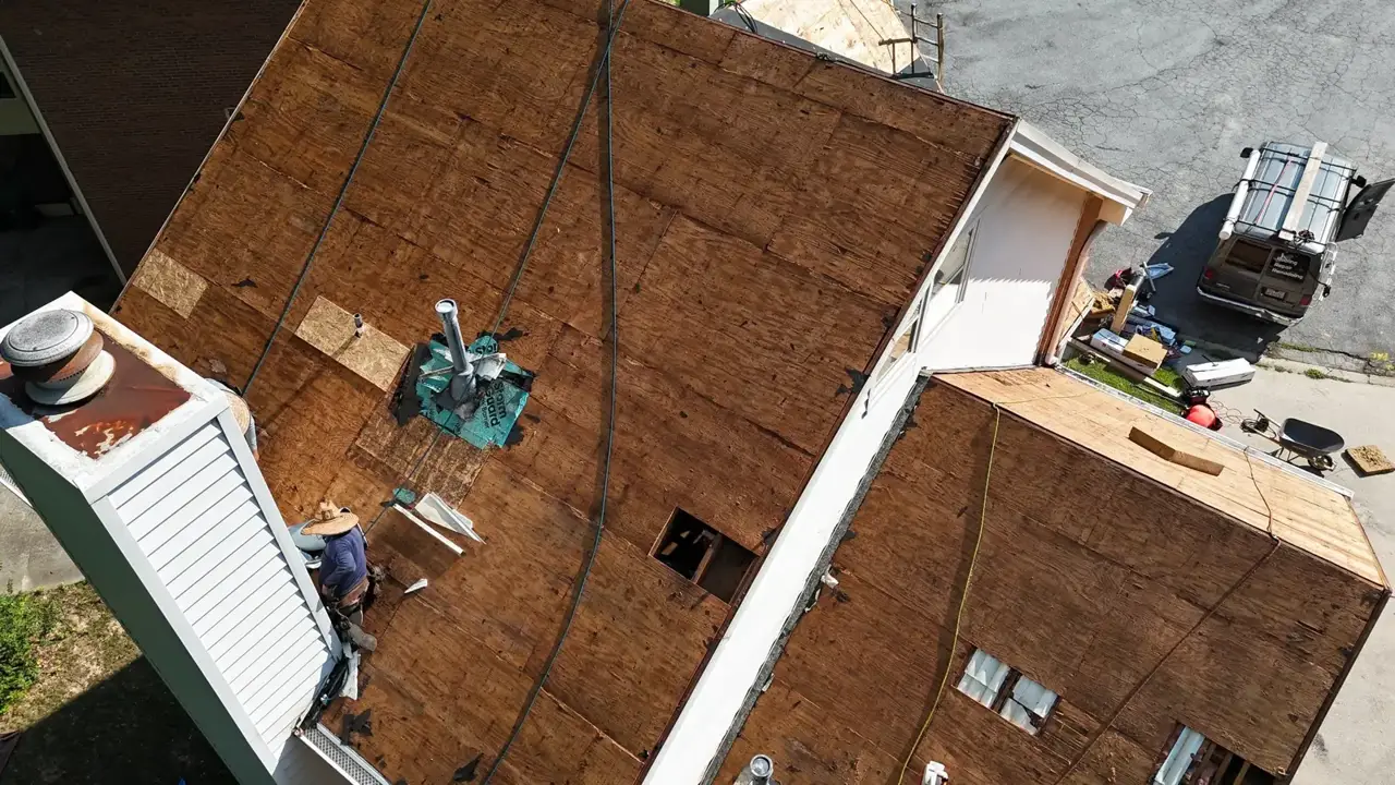 Aerial view of exposed roof decking, roof vents, siding, ladder, and construction materials in Decatur GA