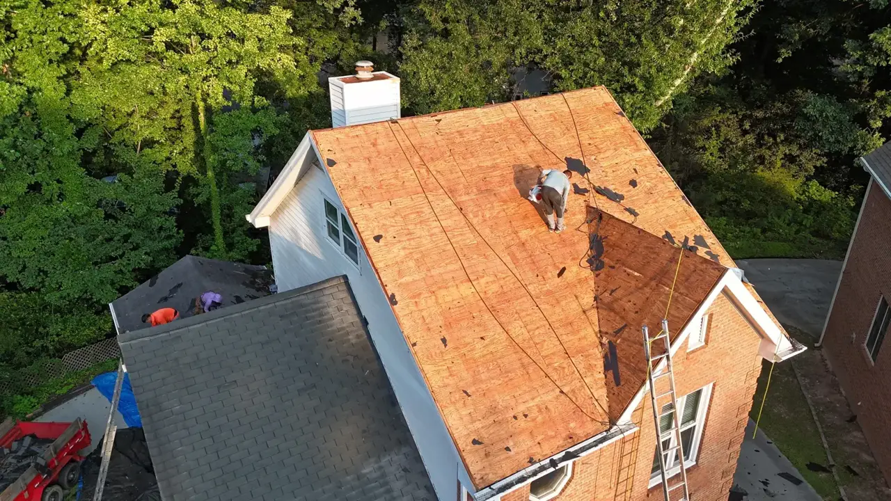 Exposed roof decking with workers, ladders, brick siding, and neighboring roof visible in Decatur GA