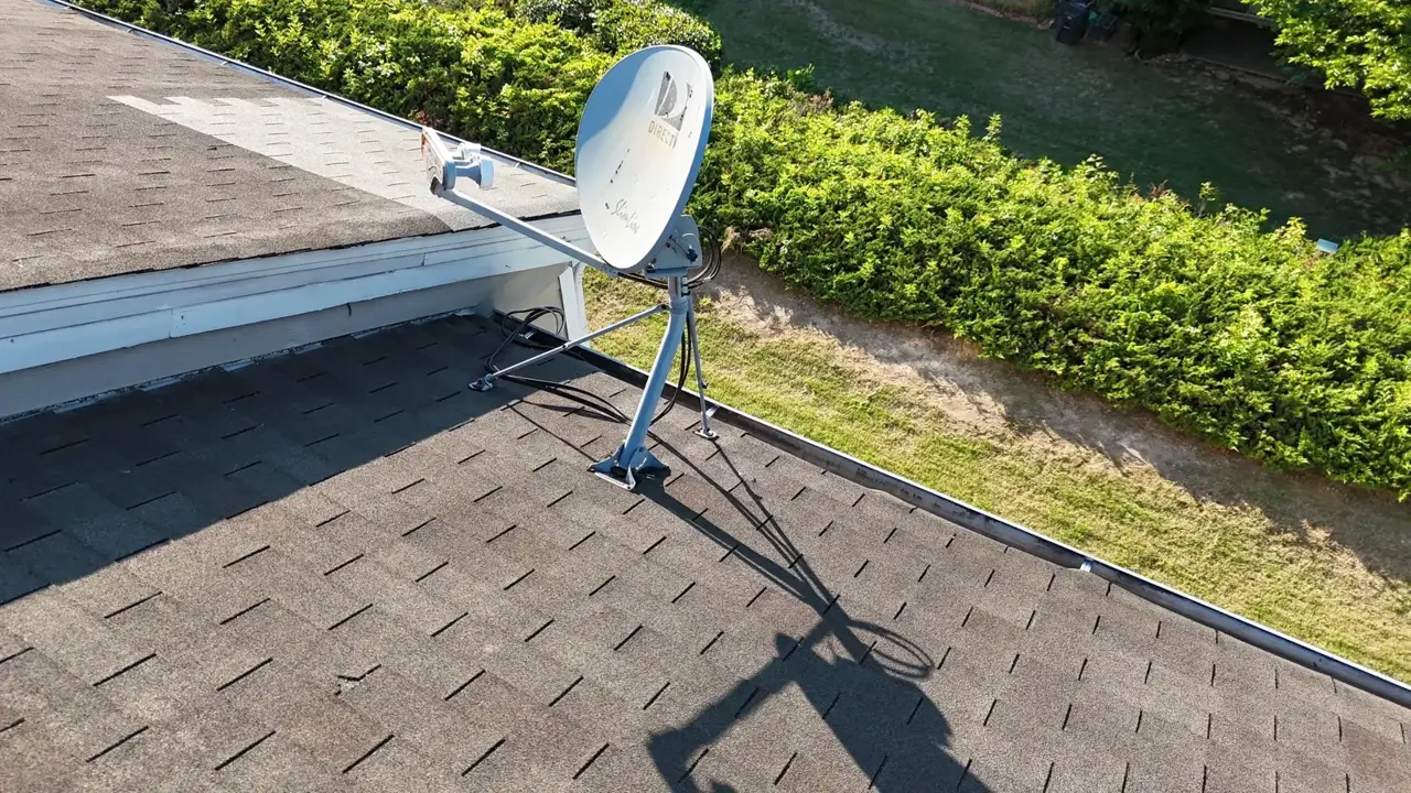 Roof shingles and satellite dish above a hedge in Duluth GA