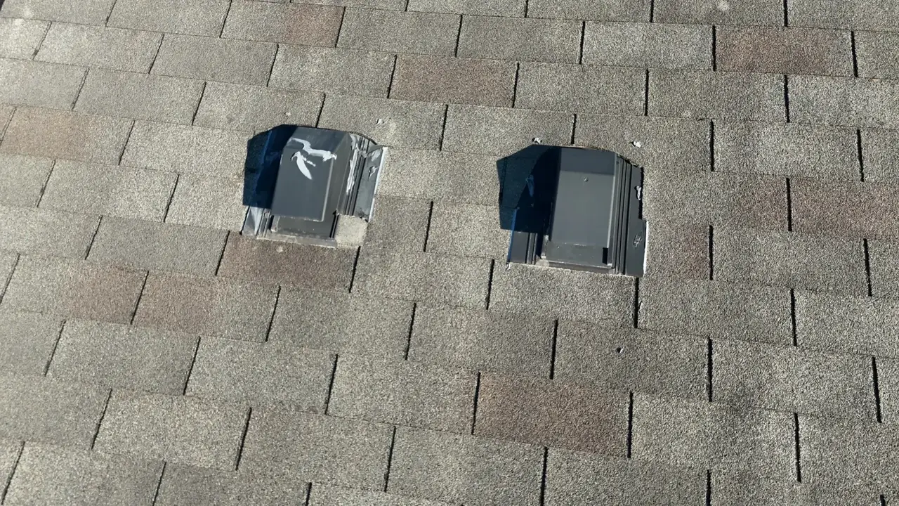 Two roof vent boots installed among weathered asphalt shingles