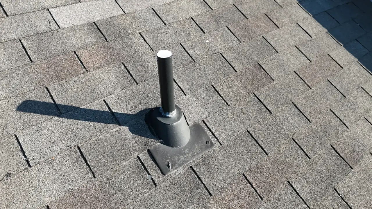 Black plumbing vent pipe projecting through asphalt roof shingles in Duluth GA