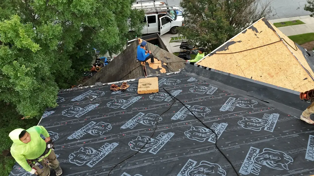 Roof replacement showing workers, exposed decking, and black underlayment in Duluth, Georgia
