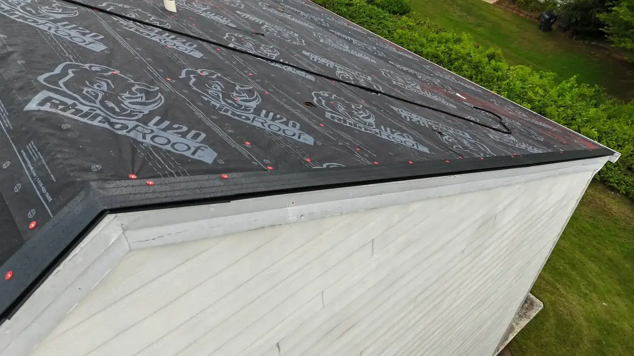 Close view shows black roof underlayment with red fasteners above white exterior siding in Duluth GA.