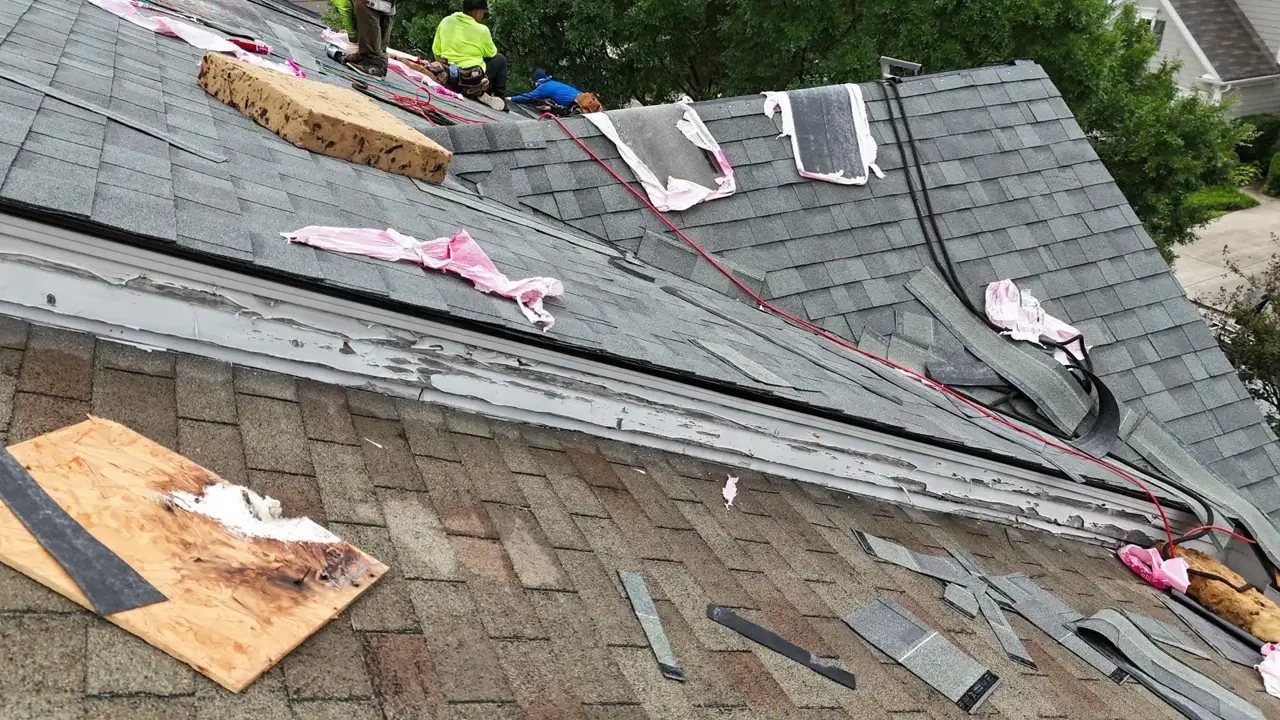 Roof replacement underway with workers, scattered shingles, tools, and exposed decking in Duluth, Georgia