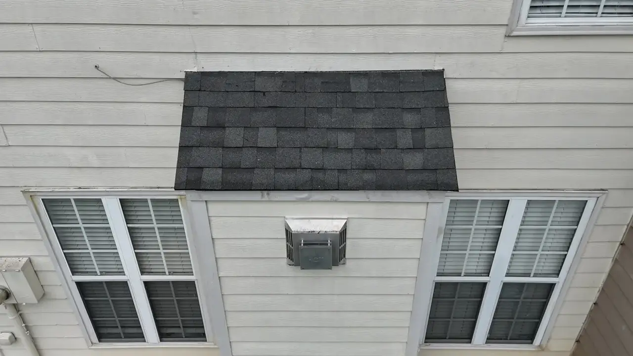 Gray shingle section above two windows on light-colored house siding