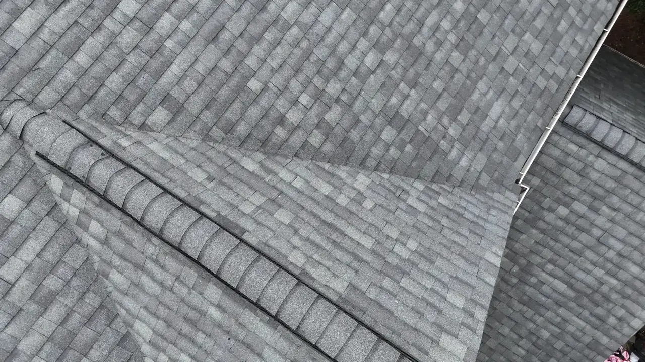 Close aerial view of overlapping gray shingles along a roof ridge