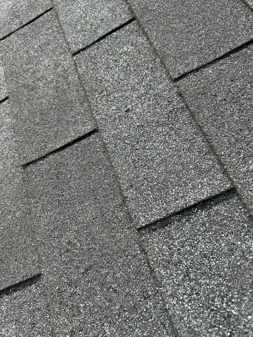 Close-up view of overlapping gray asphalt roof shingles