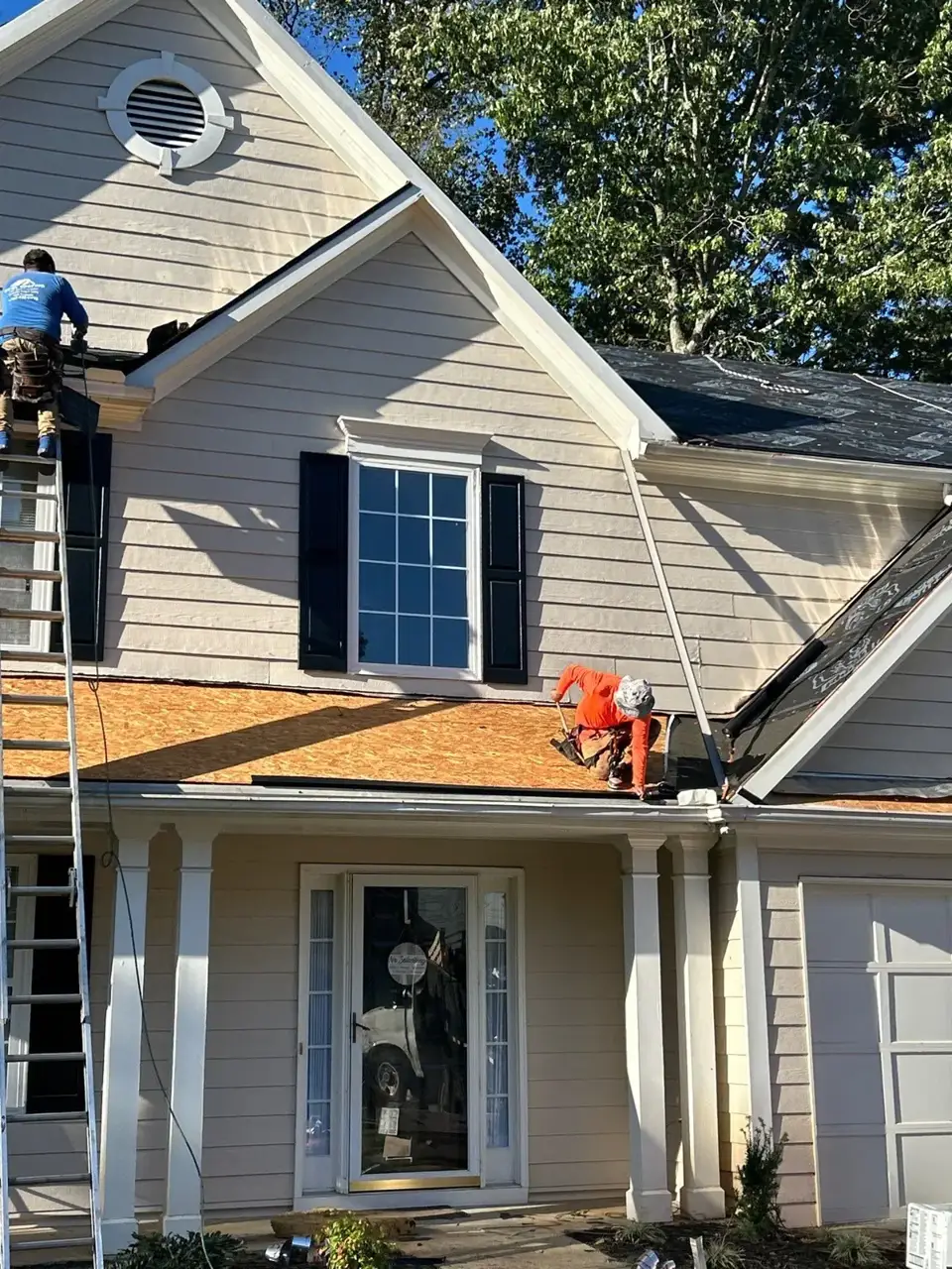 Workers install roof decking above siding and a garage in Kennesaw GA