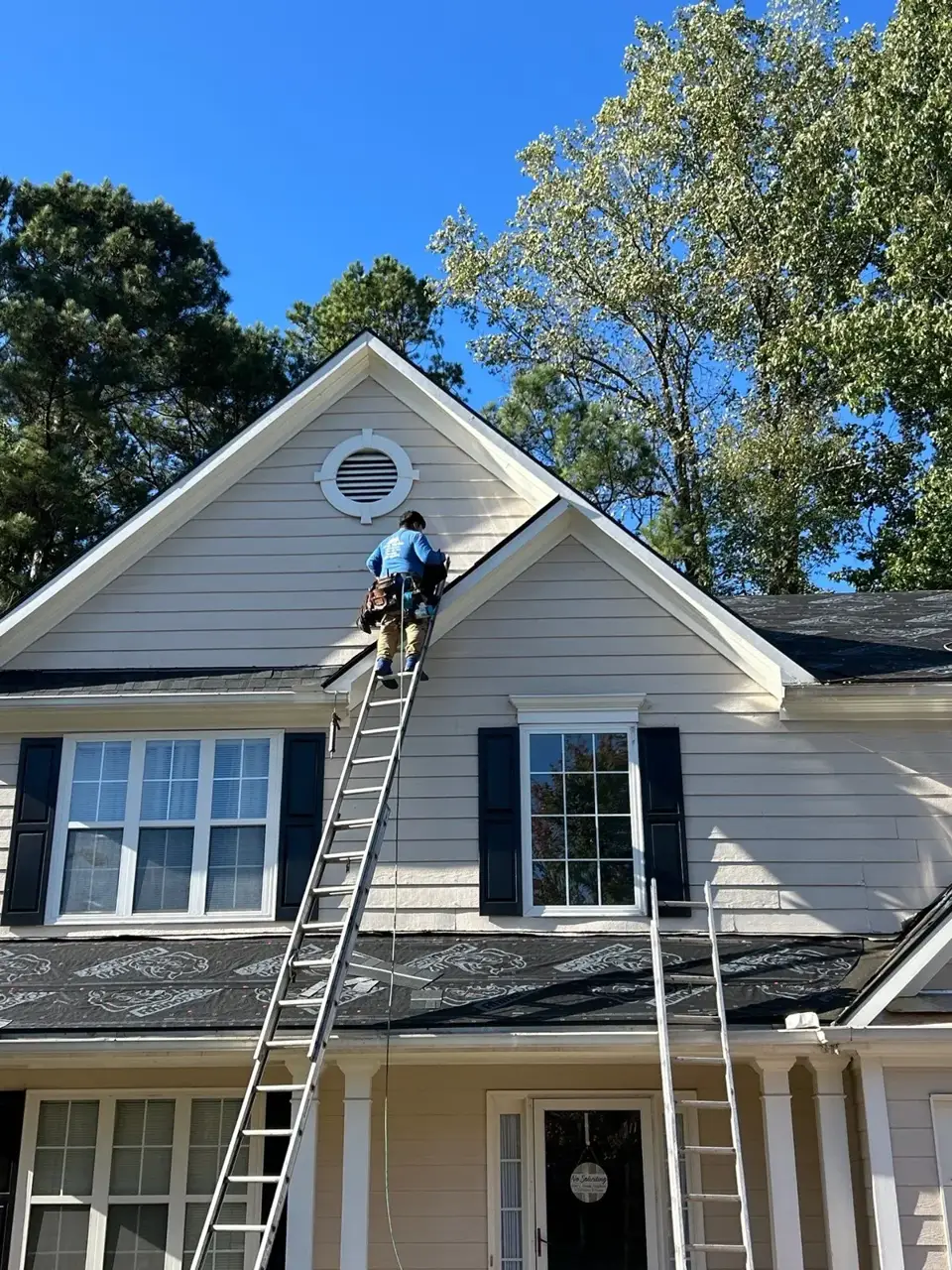 Worker accesses a roof using a ladder above protective underlayment in Kennesaw GA