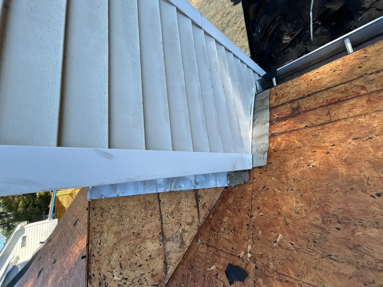 Exposed roof decking meets white siding and metal flashing on Lawrenceville GA home.