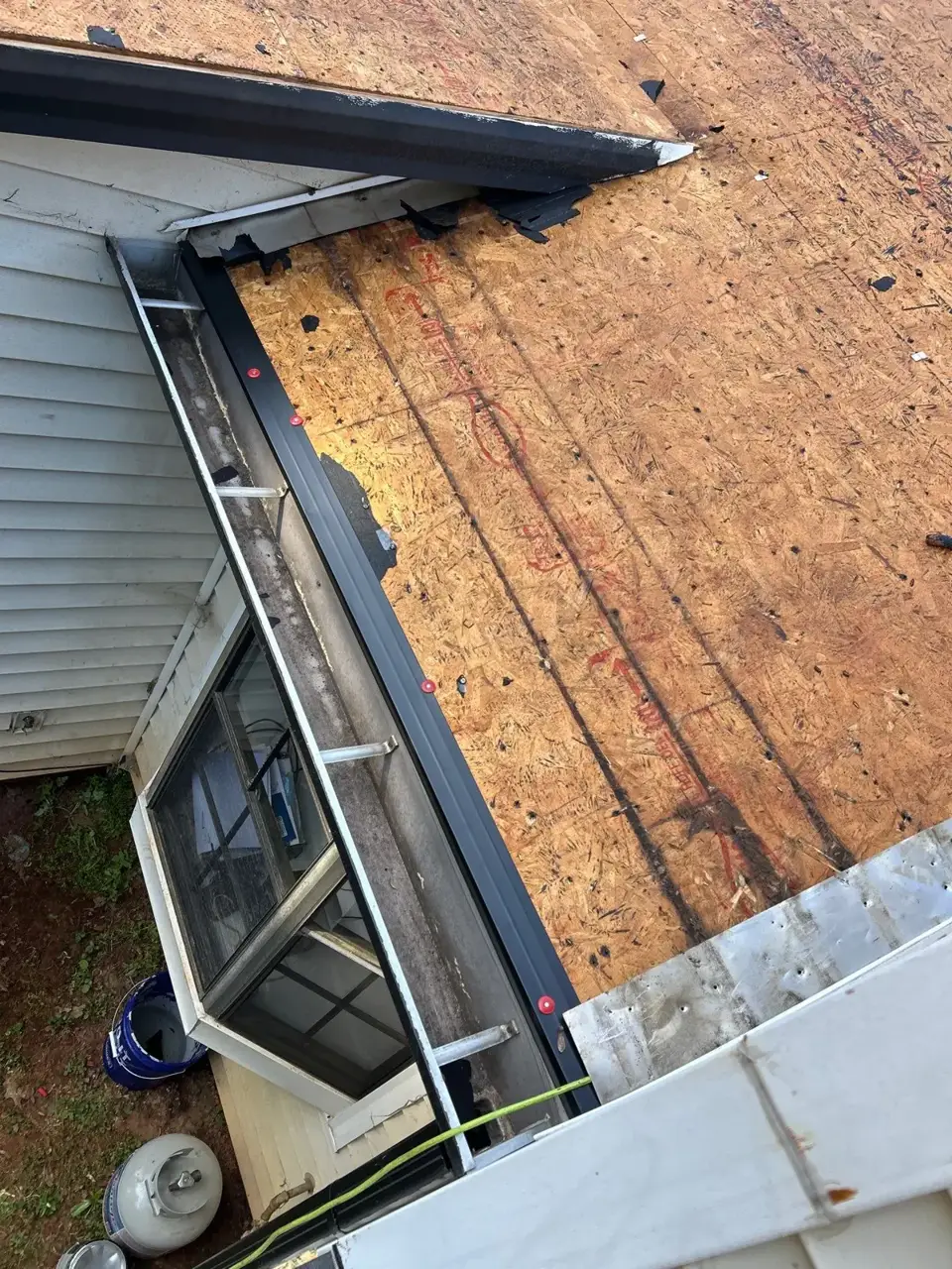 Exposed roof decking beside gray siding, gutter, and window during replacement in Lawrenceville GA