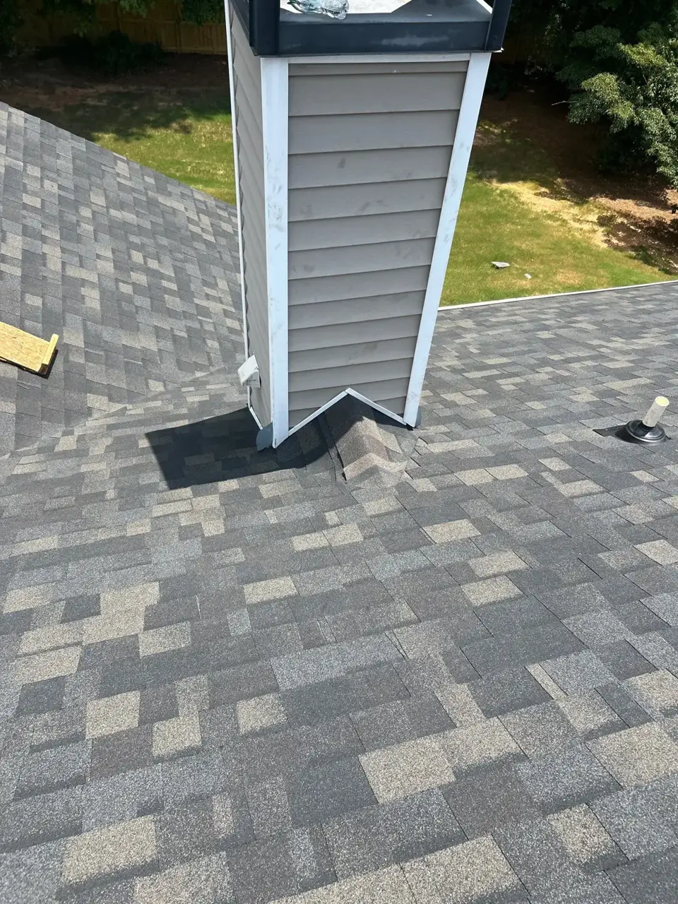 Gray shingle roof surrounding a white-sided chimney and roof vent in Loganville GA