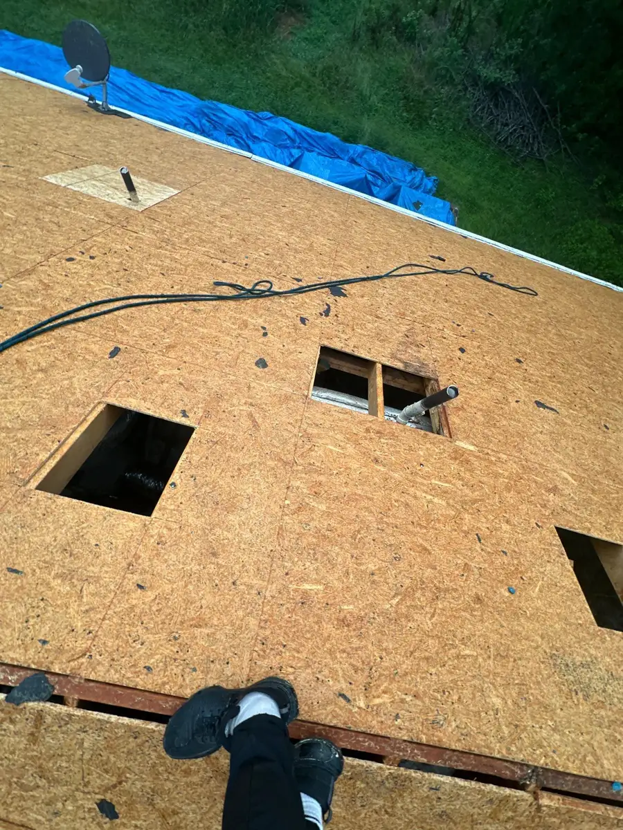 New roof decking shows openings, tools, and blue tarp along edge, Southern Premier Roofing work near Auburn GA