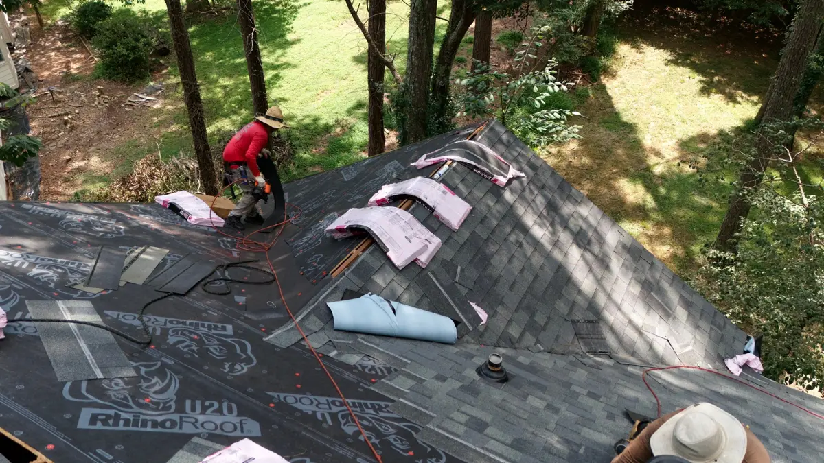 Worker and roofing supplies visible on partially shingled roof, Southern Premier Roofing work near Between GA