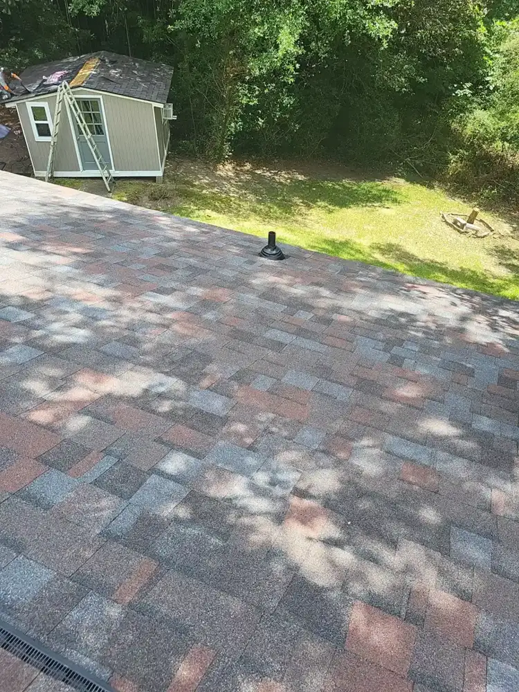 Finished multicolored shingle roof overlooking lawn and shed, Southern Premier Roofing work near Commerce GA