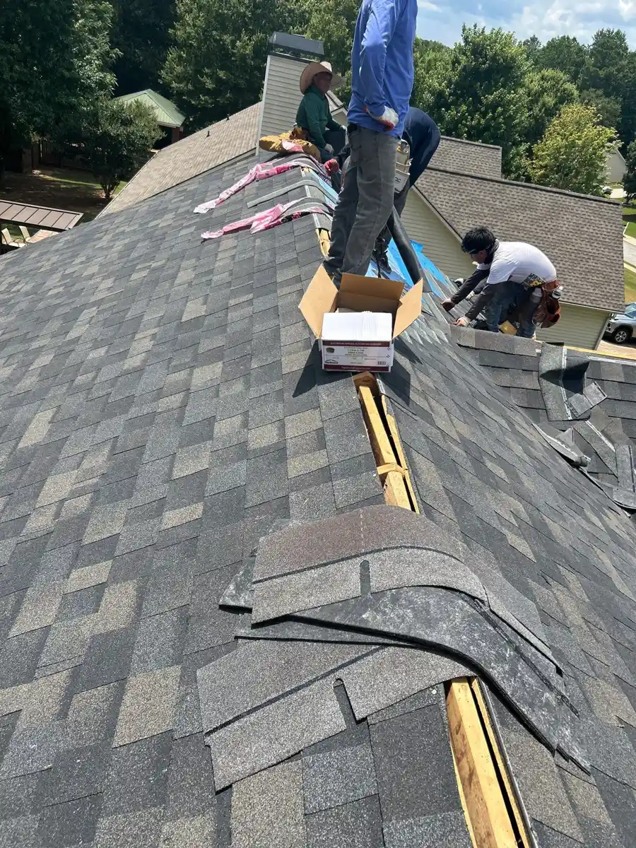 Workers installing ridge vent along roof peak with shingles nearby, Southern Premier Roofing work near Duluth GA