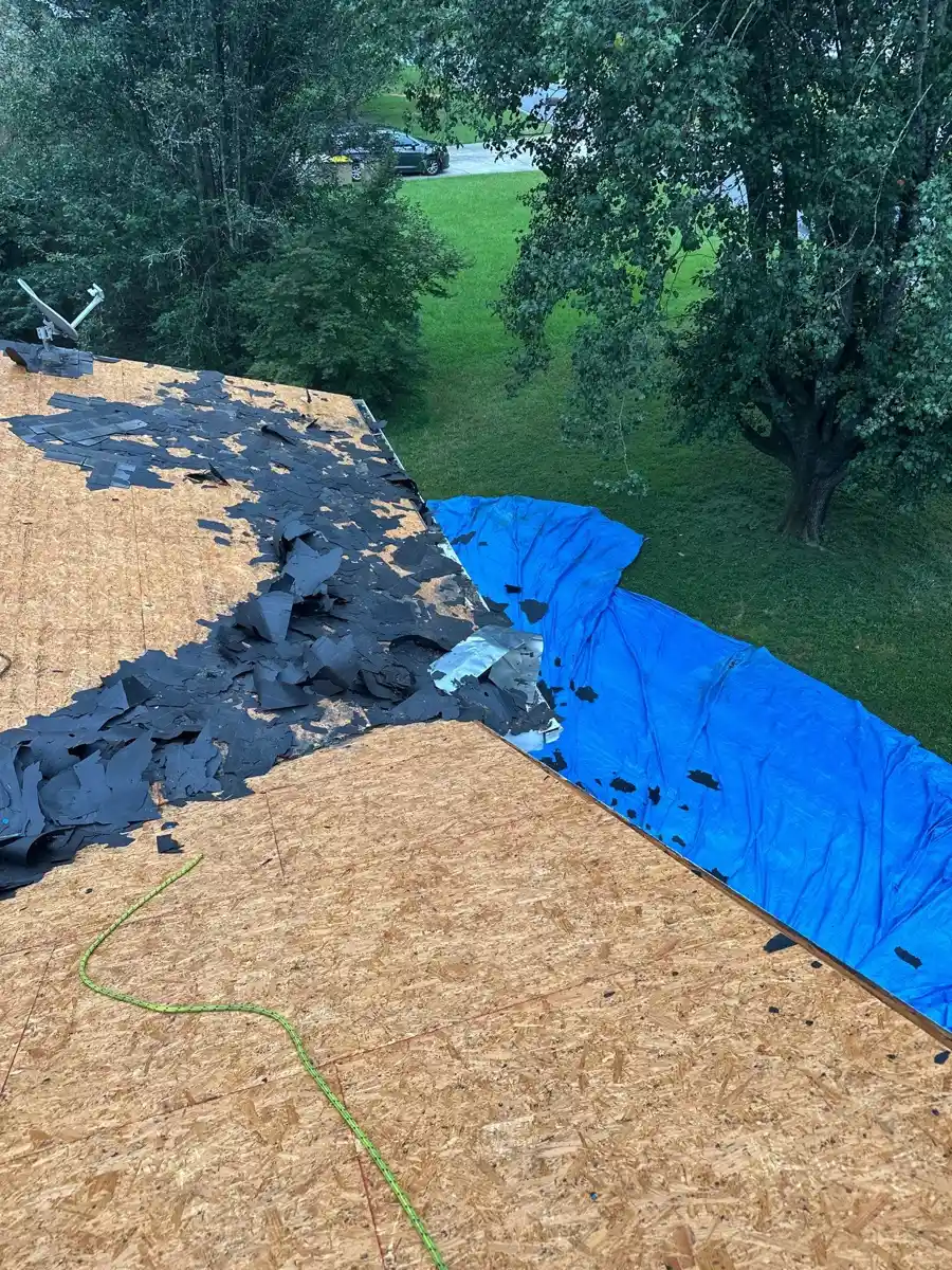 Roof decking and torn roofing materials beside blue protective tarp, Southern Premier Roofing work near Gainesville GA