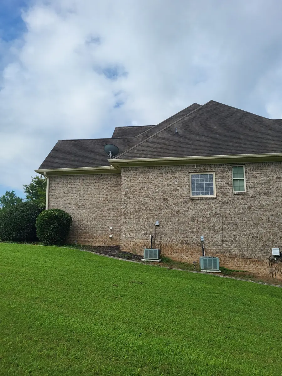 Wide view of brick home with dark shingle roof and lawn, Southern Premier Roofing work near Gillsville GA