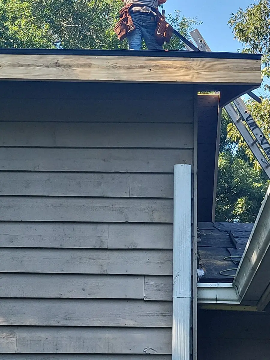 Worker handling roofing materials along exposed roof edge, Southern Premier Roofing work near Good Hope GA