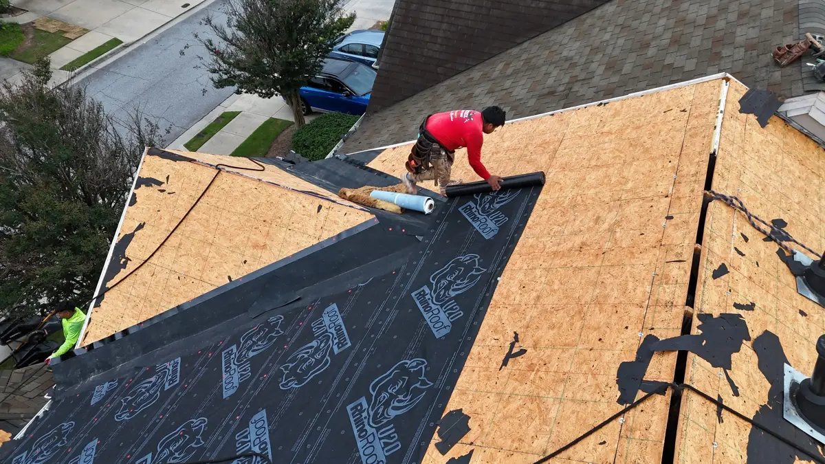 Worker installing roofing materials on exposed plywood roof deck, Southern Premier Roofing work near Ila GA