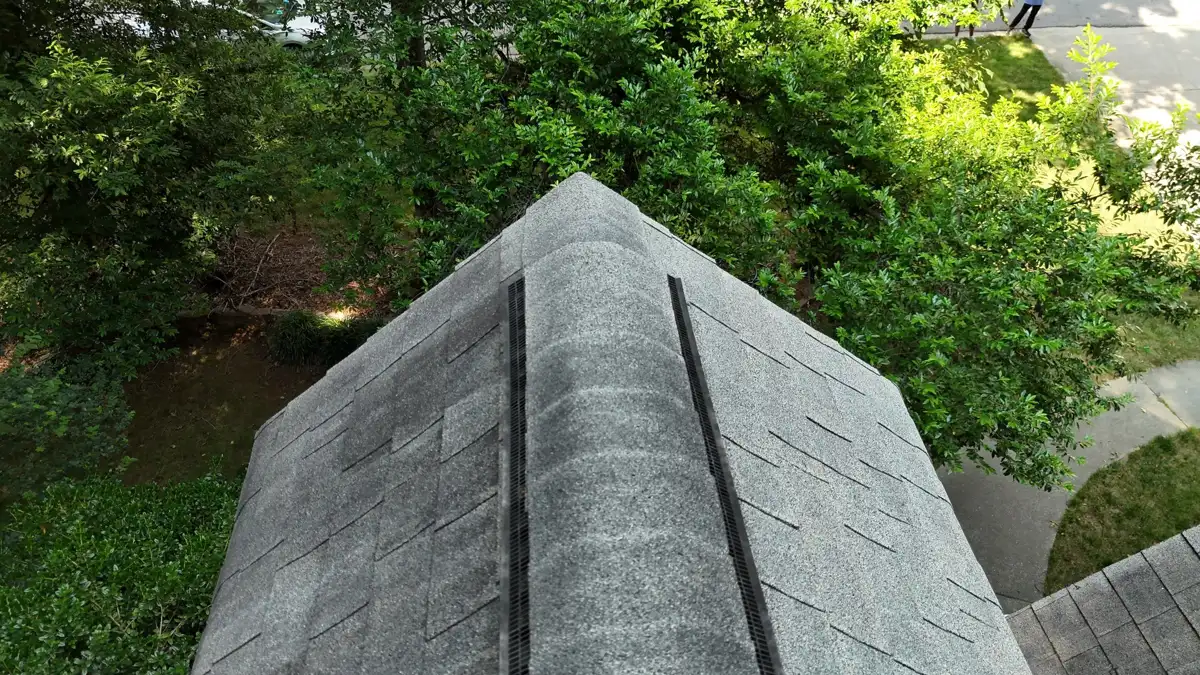 Ridge vent extending across roof peak above surrounding trees, Southern Premier Roofing work near Johns Creek GA