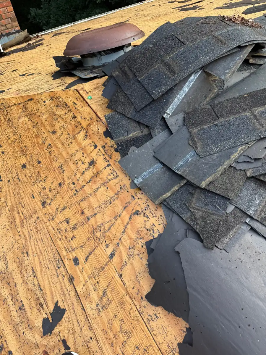 Removed shingles expose roof decking beside remaining roof materials, Southern Premier Roofing work near Lilburn GA