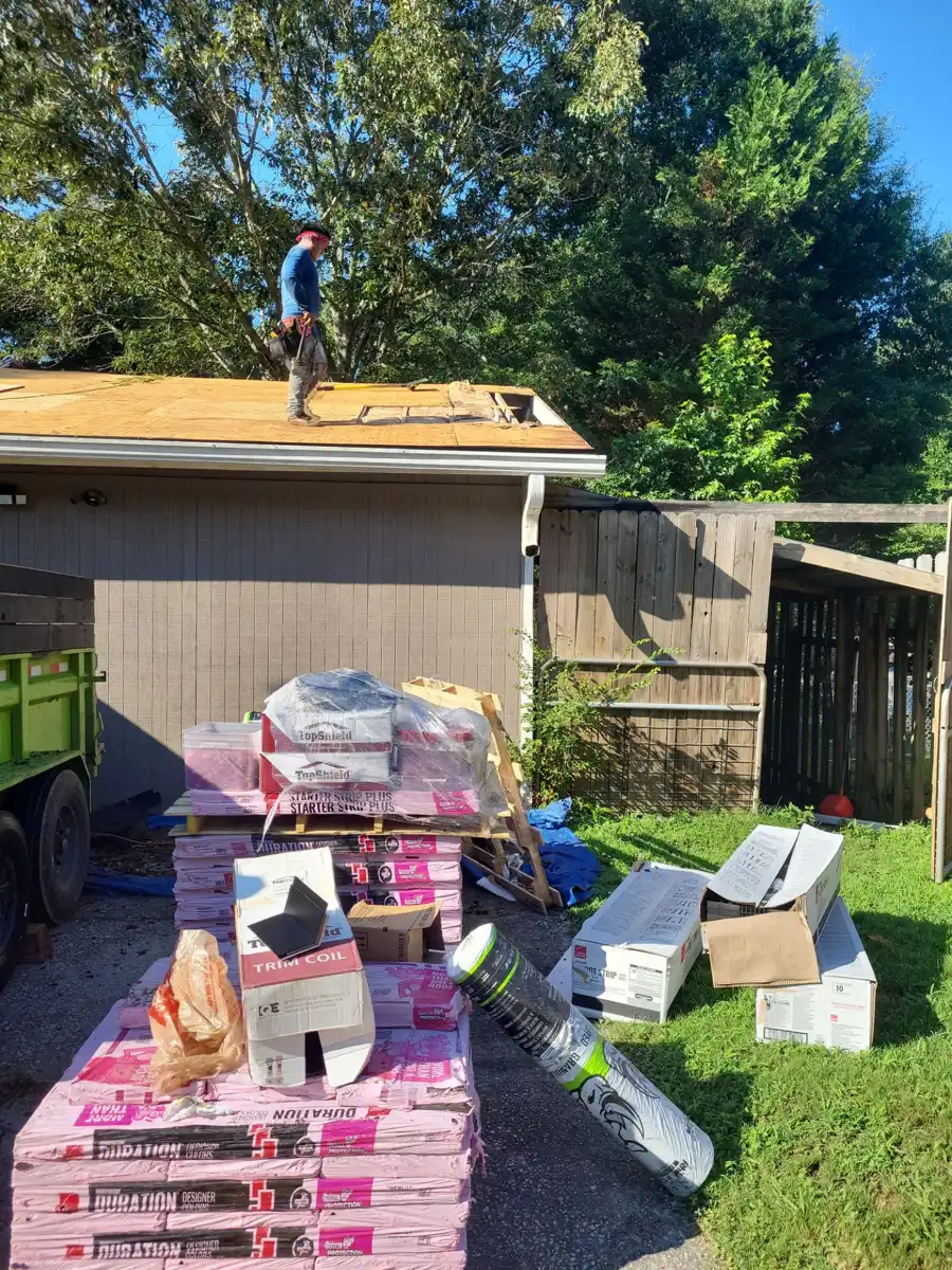Roofing worker standing on deck beside stacked roofing materials, Southern Premier Roofing work near Loganville GA