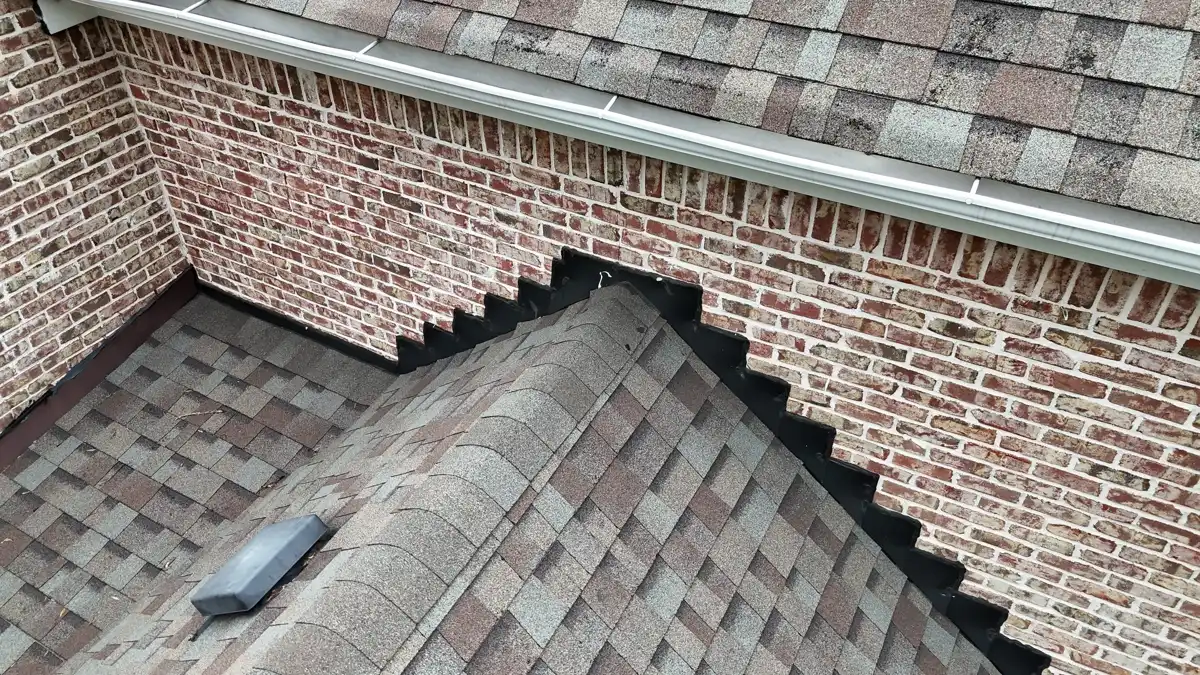 Completed shingles and ridge cap meet brick walls and metal gutters, Southern Premier Roofing work near North High Shoals GA