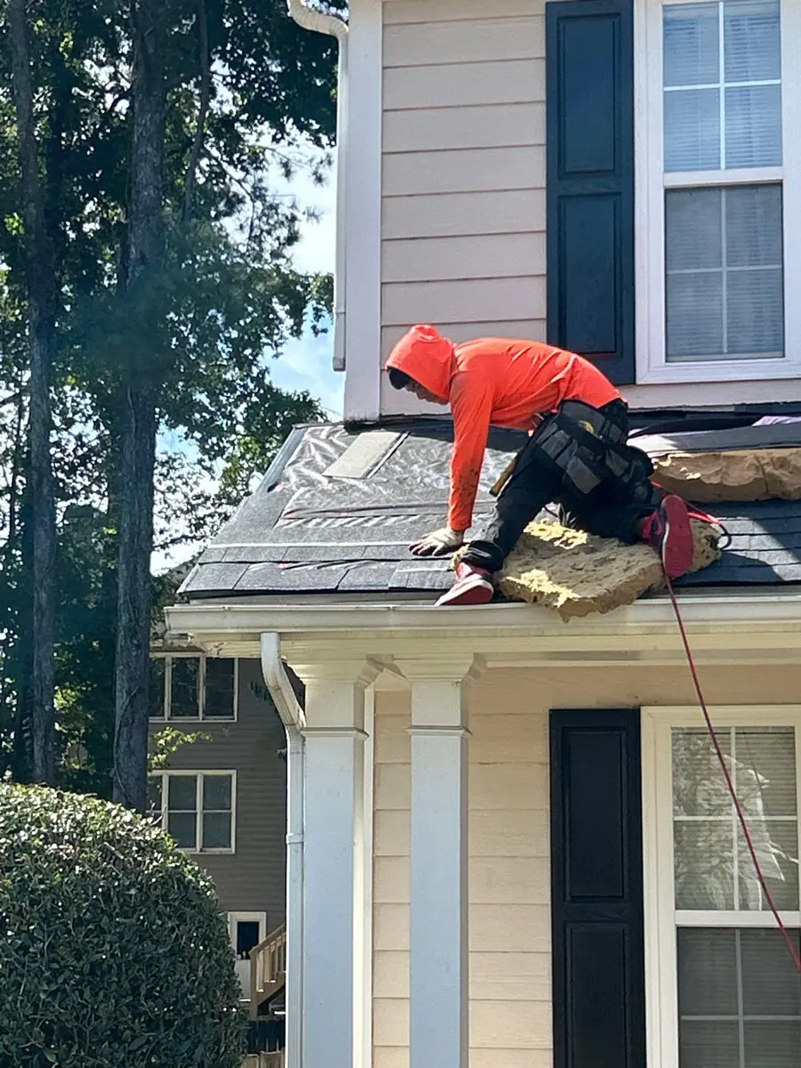 Worker installing shingles on small porch roof near house entry, Southern Premier Roofing work near Oakwood GA